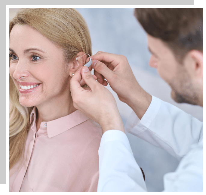 Audiologist fitting a patient with hearing aids